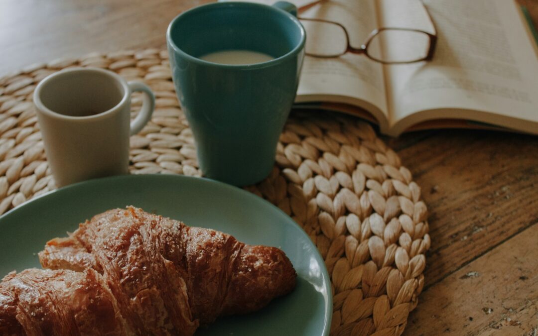 a blue plate topped with croissants next to a cup of coffee
